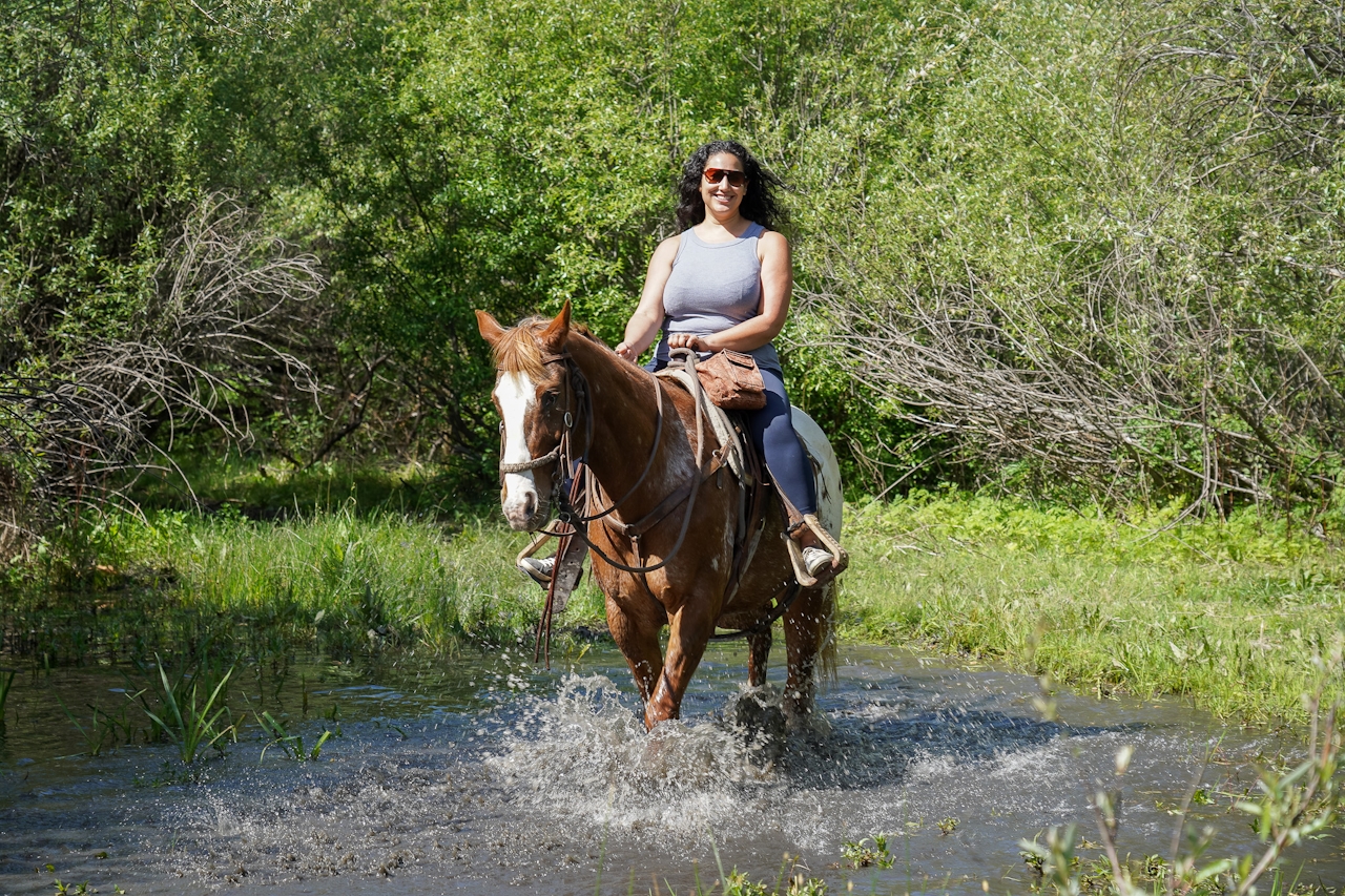 A woman on a guided horseback ride with Central Coast Trailrides is going through a puddle of water