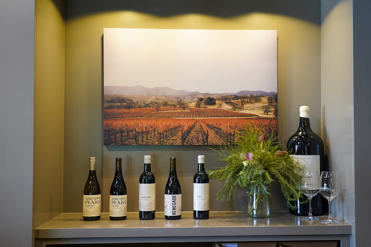 The wine bottles lined up neatly in front of a vineyard photo inside Ancient Peaks Winery Tasting Room 