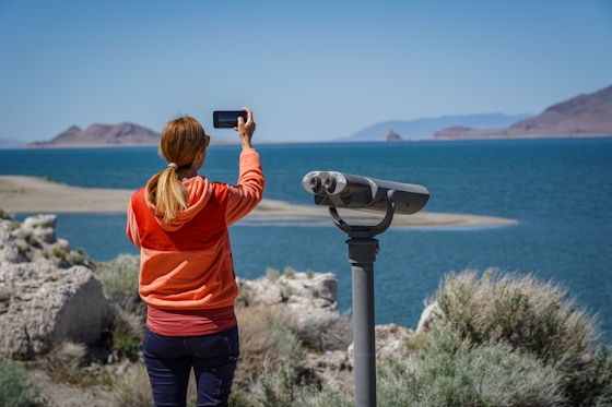 A woman takes a photo of Pyramid Lake with her phone 